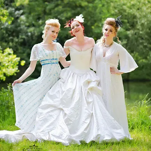 A bride and 2 bridesmaids posing together in woods