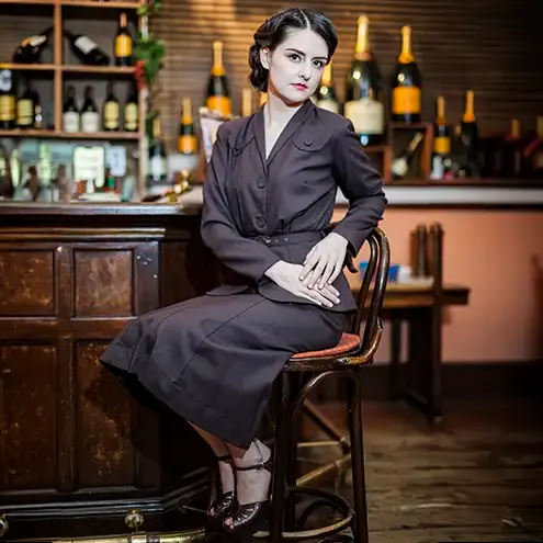 A girt wearing a 1920s style outfit sat at a bar, vintage, commercial photography