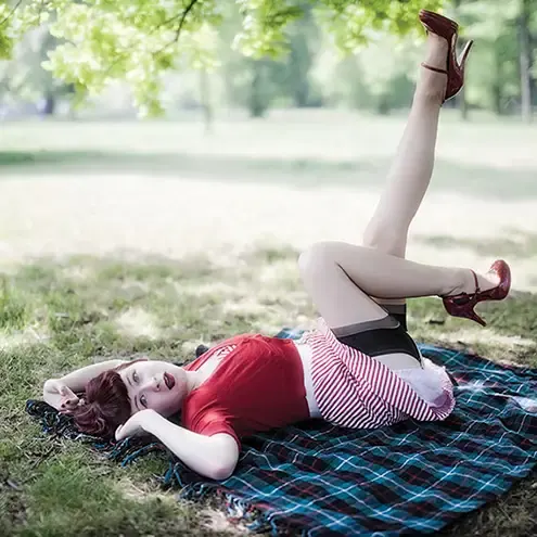 A vintage style pinup girl reclining on the grass in Hyde Park