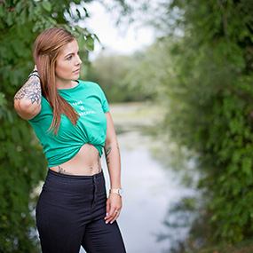 A model in a green t-shirt and jeans posing by a lake